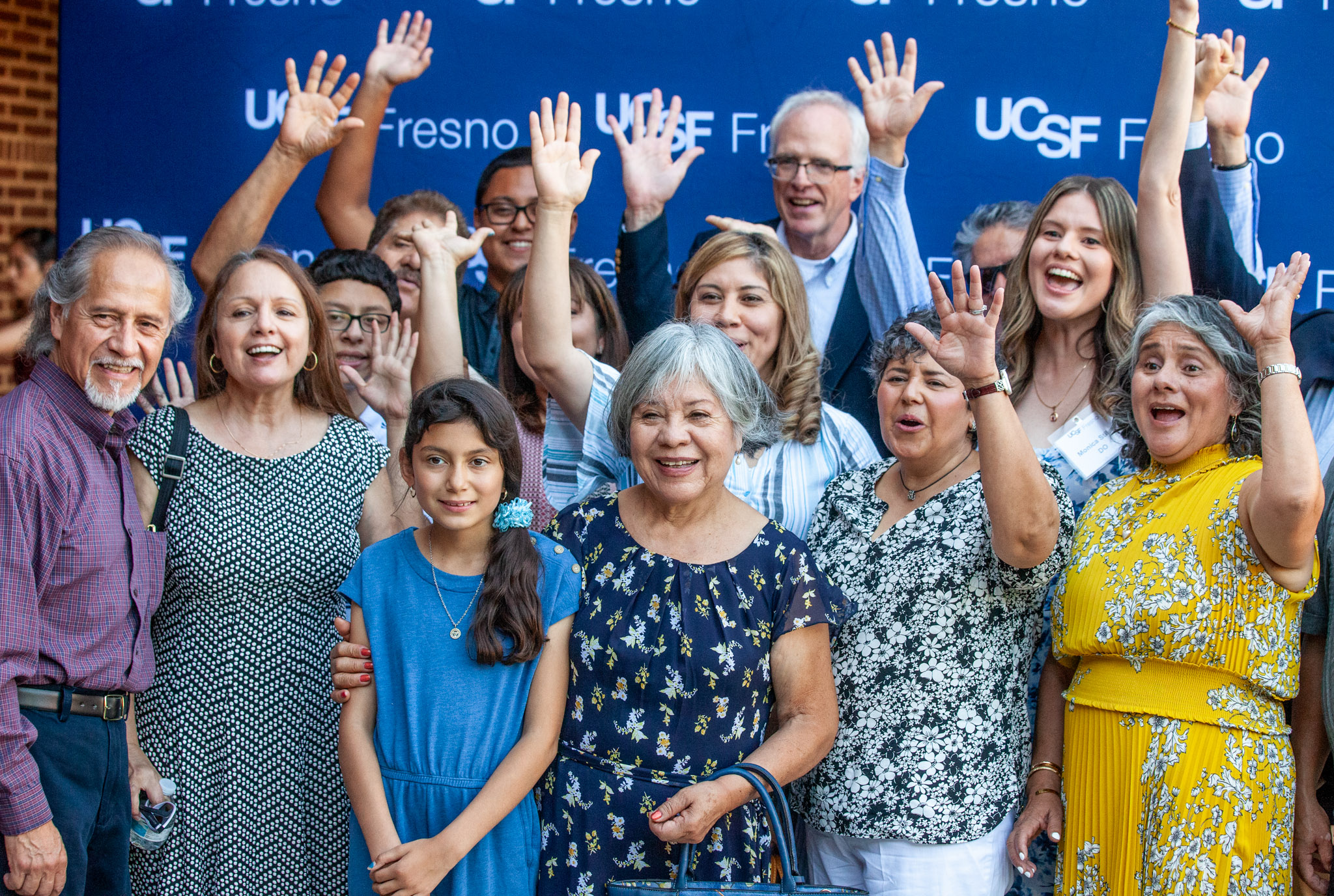 Family of a graduate celebrating in front of UCSF Fresno backdrop