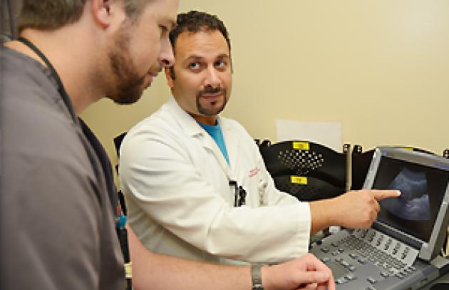 A medical fellow consults with a technician on imaging results