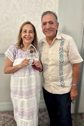 Dr. Katherine A. Flores holds an award standing next to her husband Juan Flores