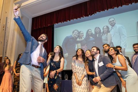 Graduates on stage take a selfie at UCSF Fresno commencement 