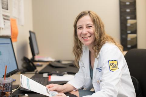 Dr. Marina Roytman sitting at a computer smiling at camera