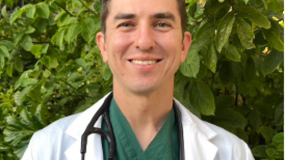 Medical student wearing a white coat smiles at the camera