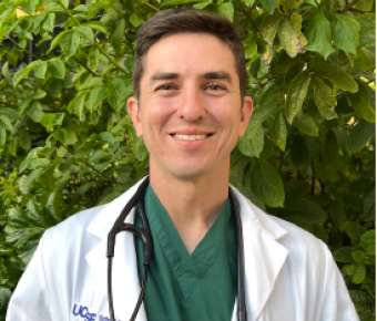 Medical student wearing a white coat smiles at the camera