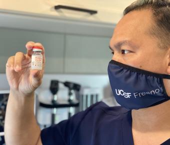 Doctor looks at Moderna COVID-19 vaccine vial