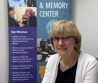 Loren Alving, MD, sits in front of a UCSF Fresno Alzheimer and Memory Center sign