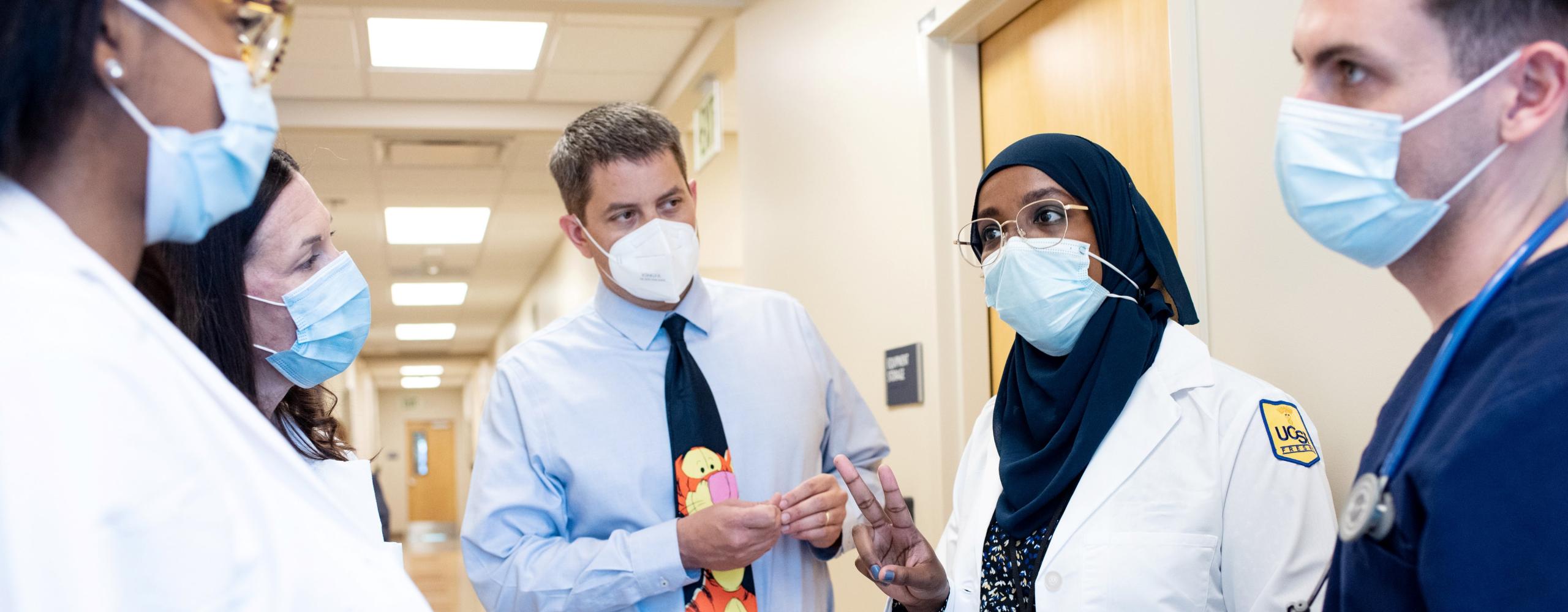 Woman talking to medical students in hospital hallway.