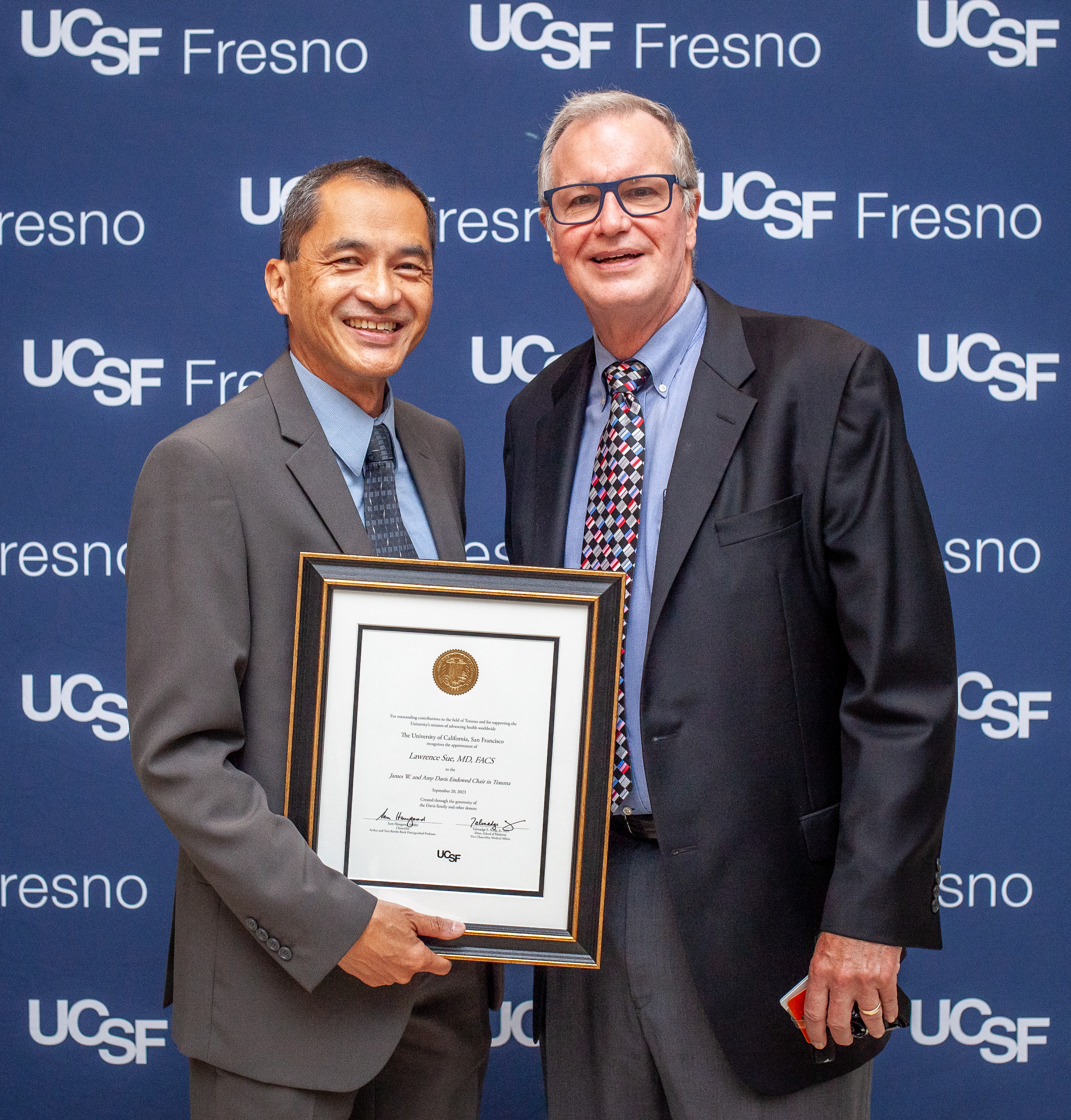 Two men posing shaking hands and presenting after one received an awarded plaque