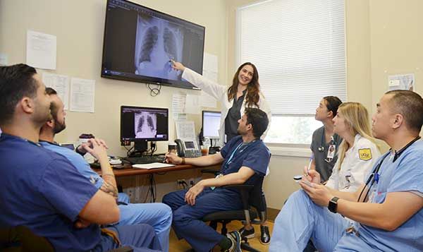 IM residents huddled around a computer taking notes