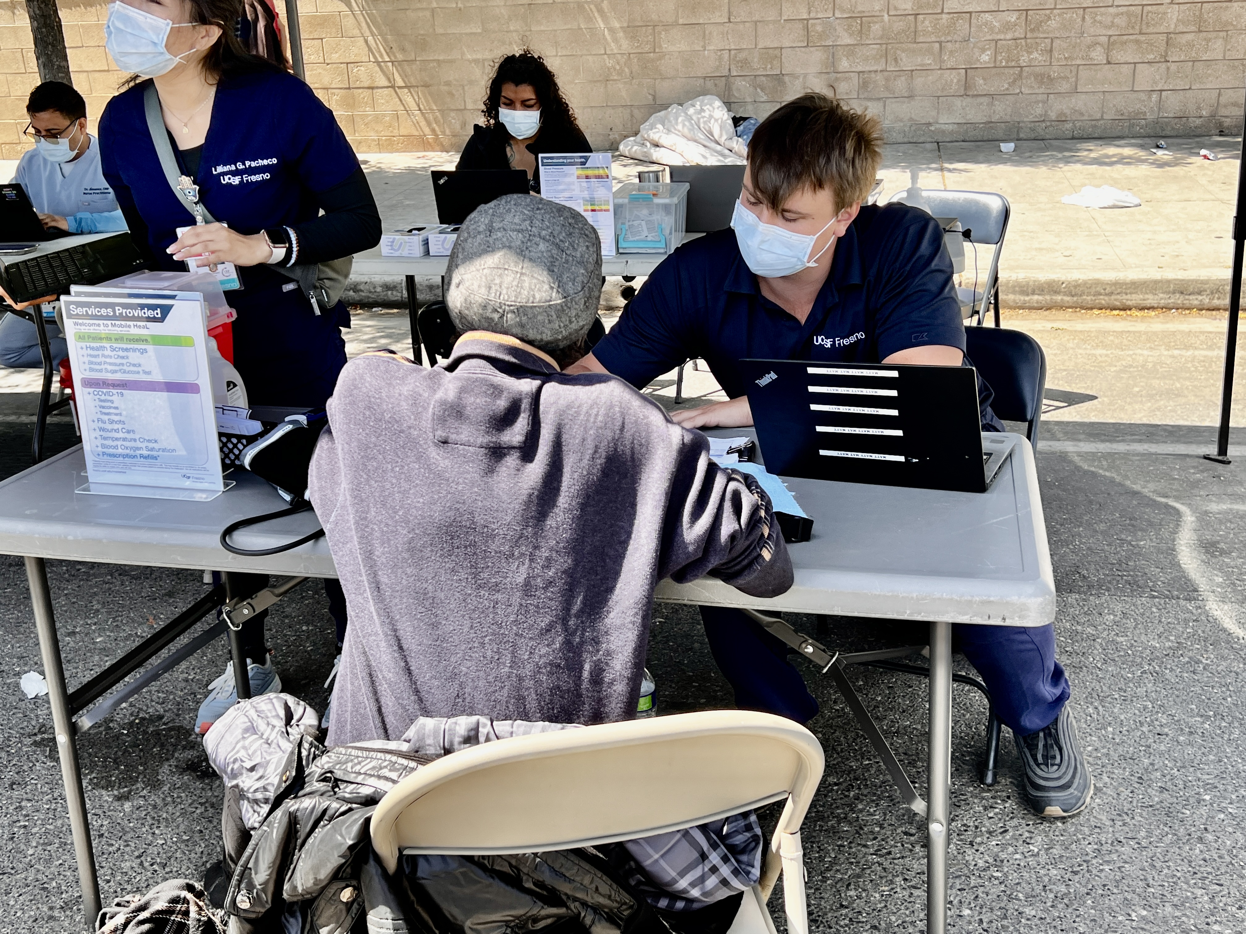 Medical staff sitting and helping a patient at unsheltered clinic.