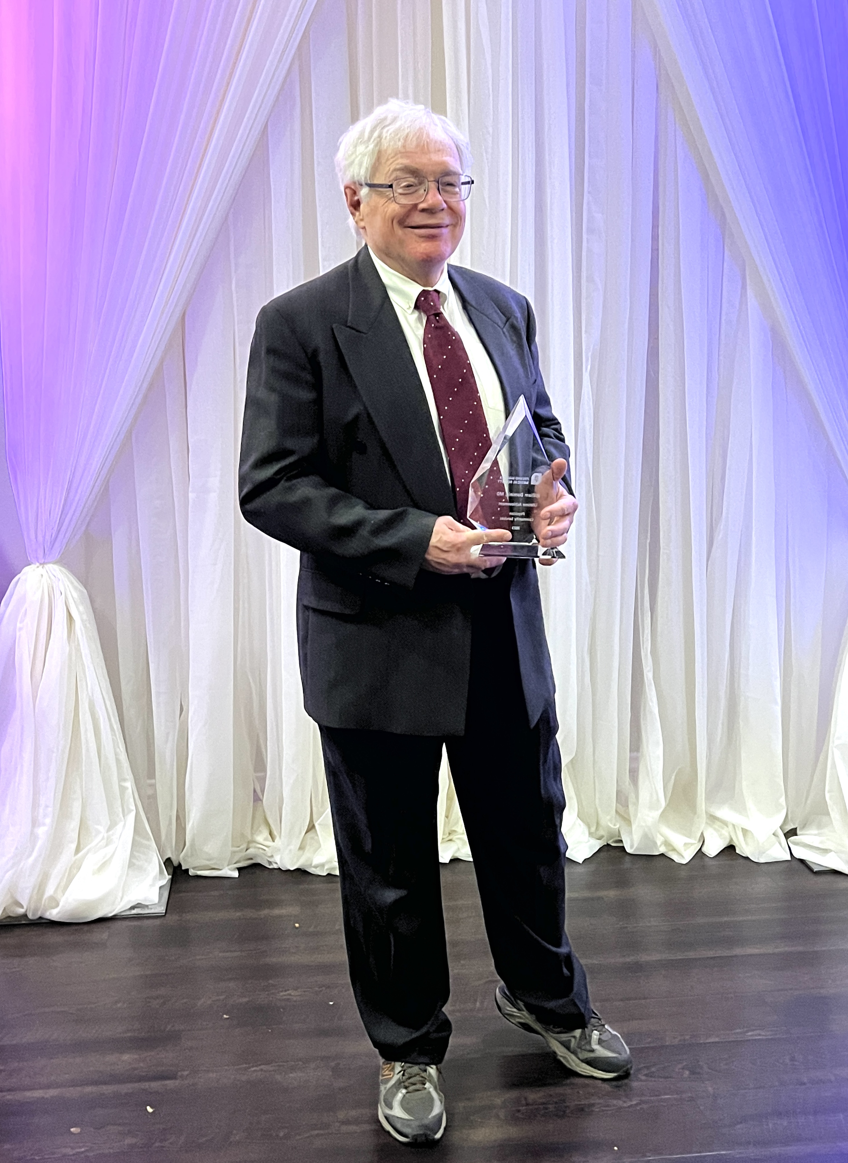 Dr. William Dominic posing with an award